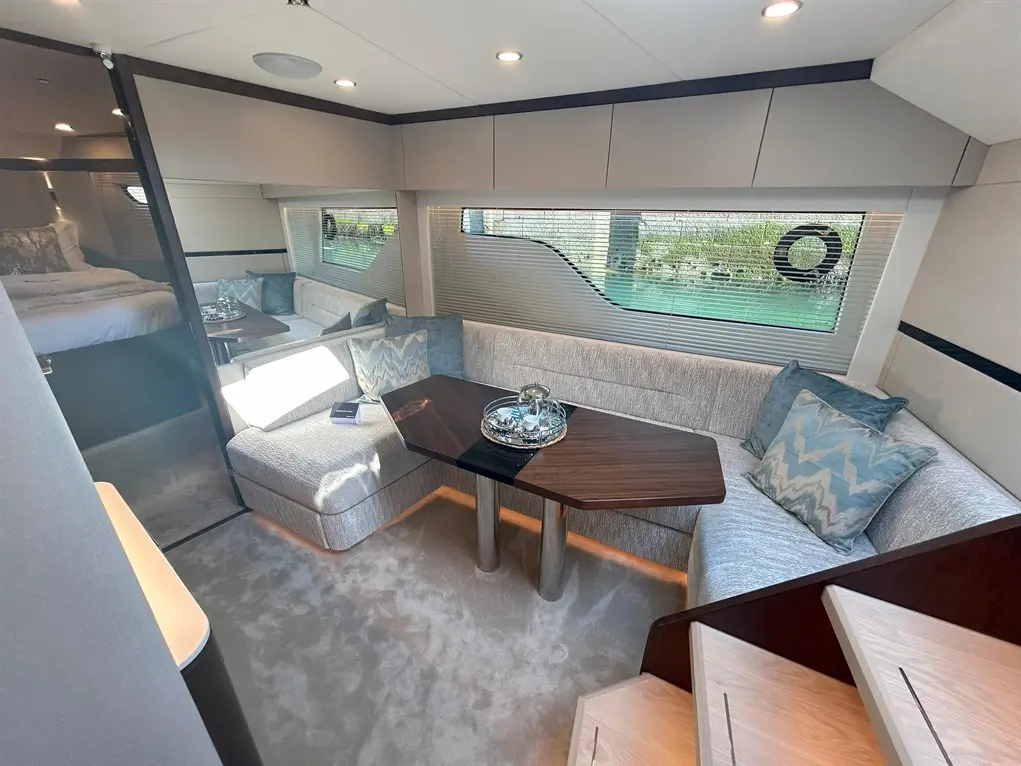 Luxurious yacht interior featuring a sleek lounge area, elegant decor, and a view through large windows with blinds.